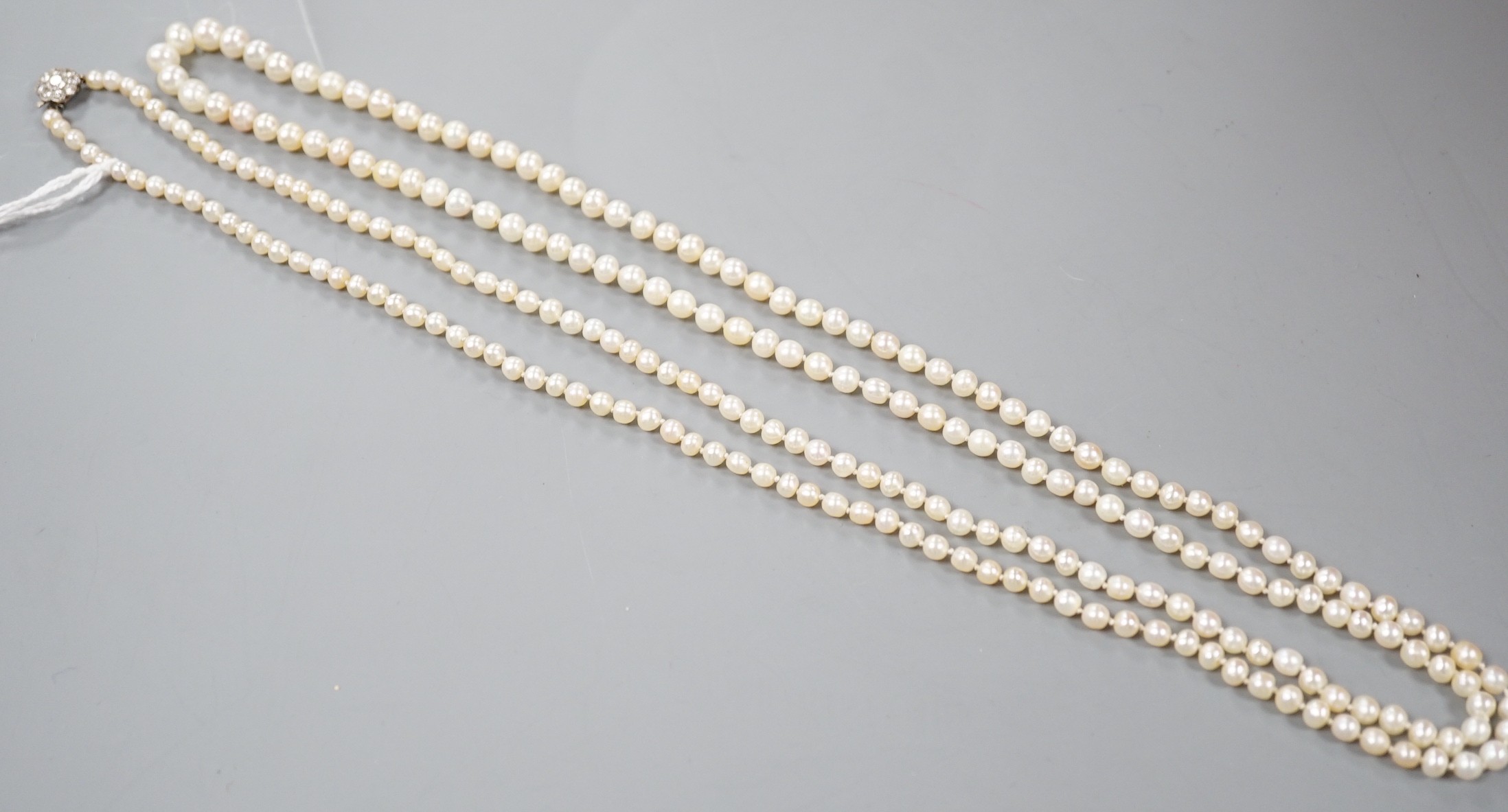 An early 20th century single strand possibly part natural? and part cultured pearl necklace, with diamond cluster set white metal clasp, 112cm.